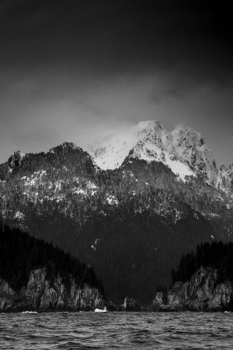 Mountains of the Aialik Peninsula, Alaska. Mountains jut from the ocean as waves crash at their bases, Kenai Fjords National Park. Black and white.