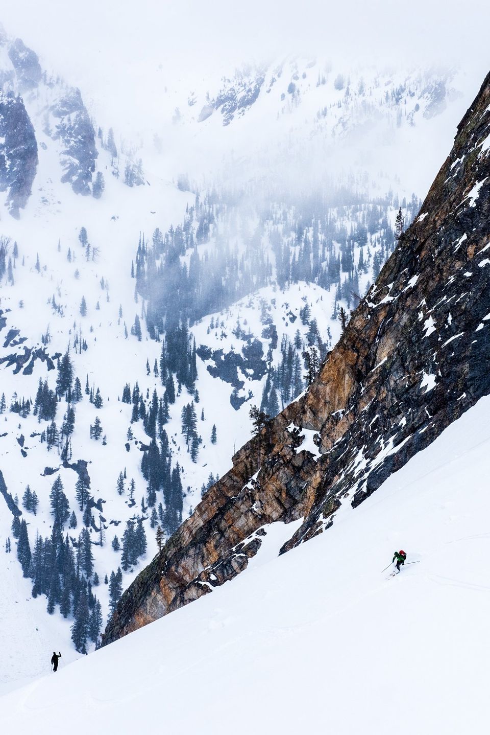 Needle in a Snowpack. Two skiers in the vast winter wilderness are tiny needles in a snowpack.