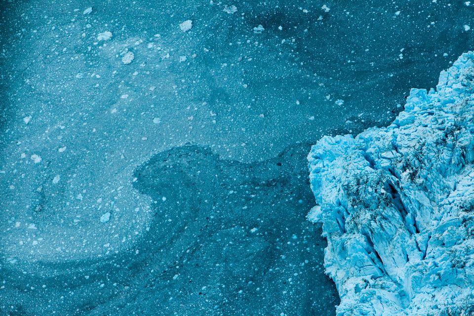 Prince William Sound, Alaska. Shot from a small Cessna: sea ice of varying thickness forms wave patterns in an eddy off a protruding glacier.