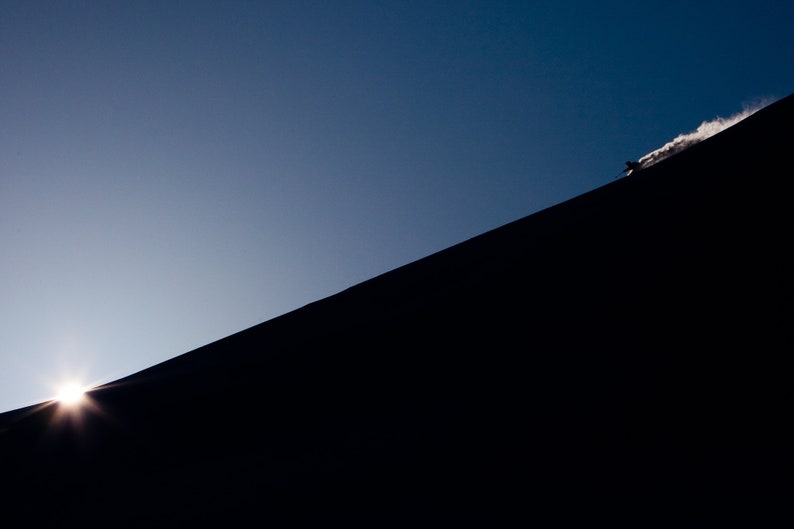 Skiing First Light. A backcountry skier descends a ridge at first light.