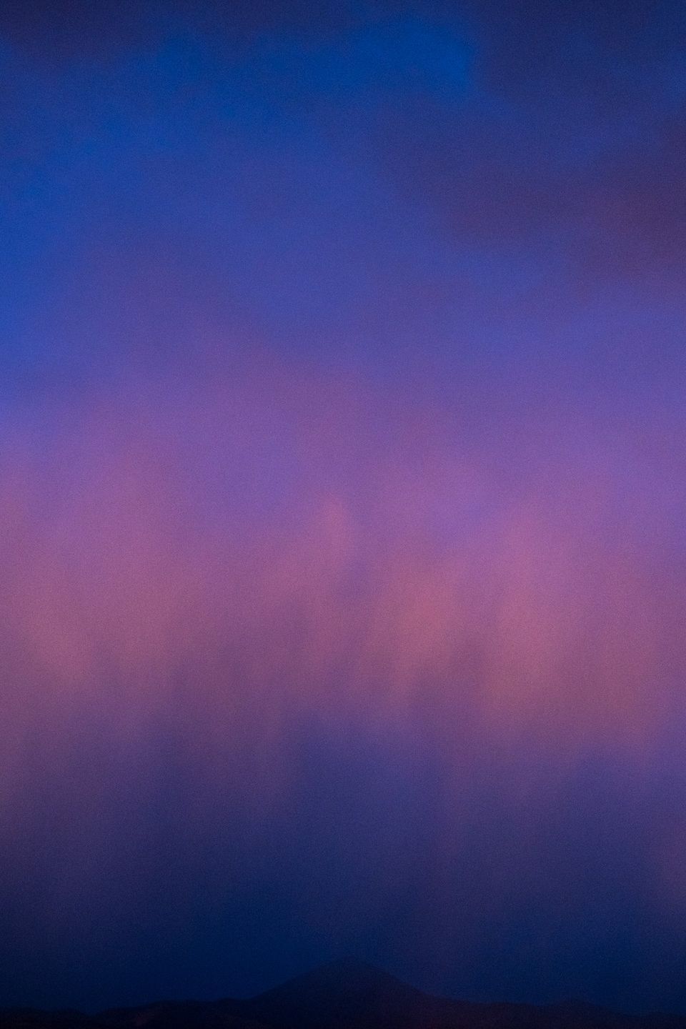 Sunset, Smoky Mountains, Idaho. The faint silhouette of a distant peak hides below clouds catching the last light of day.
